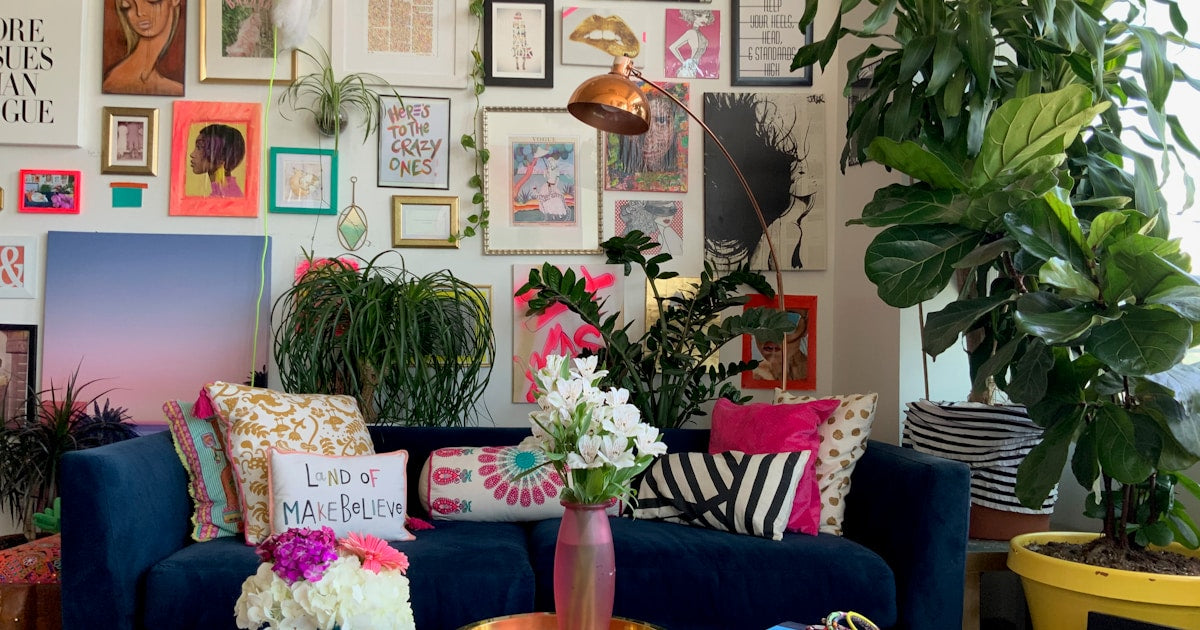A stylish living room with a blue couch and framed art prints on the wall showing how to choose art for every room in your home